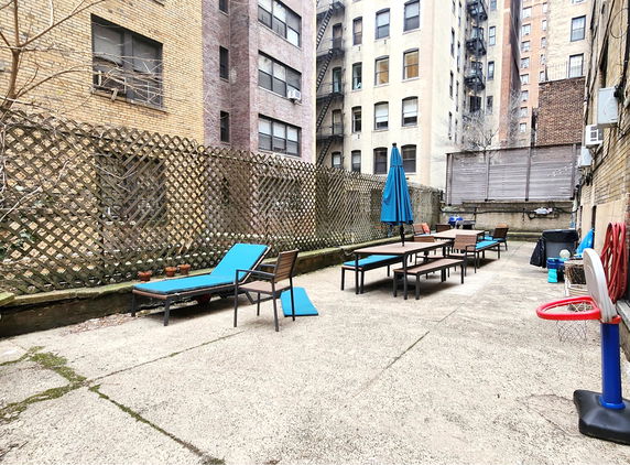 Outdoor area with blue lounge chairs, tables, and a small basketball hoop.