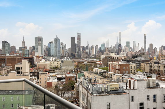 Panoramic view of a city skyline with numerous skyscrapers and buildings under a blue sky.