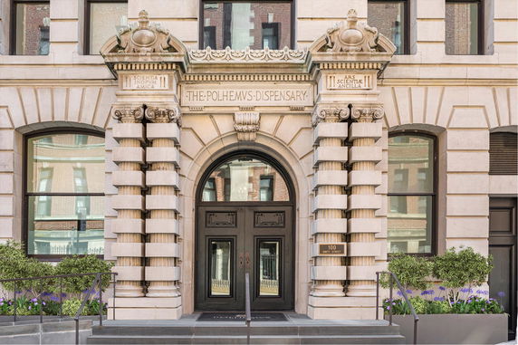 Front view of a historic building entrance with ornate details and stone columns.
