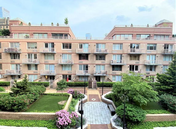 Front view of a multi-story apartment building with balconies and a landscaped courtyard.