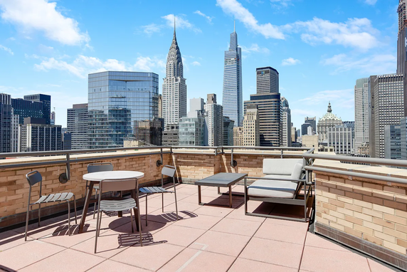 Rooftop area with seating and city skyline view.