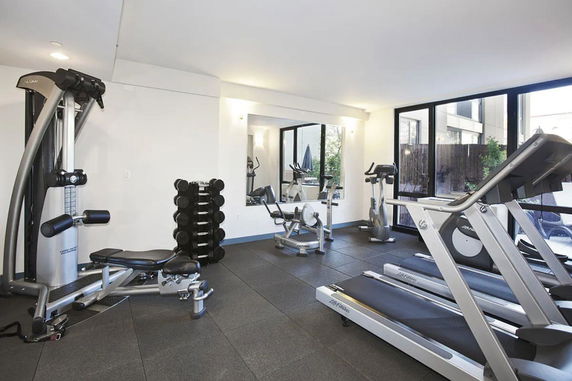 Indoor gym area with exercise equipment and weights.