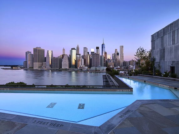 Panoramic view of a swimming pool overlooking a city skyline.
