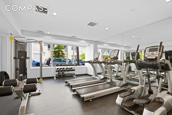 Indoor gym area with treadmills, exercise machines, and weights.