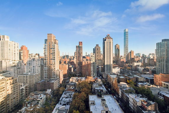 Wide angle view of a city skyline with tall buildings under a clear blue sky.