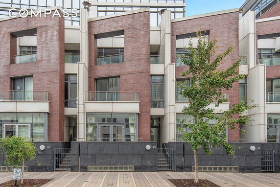 Front view of a modern multi-story building with large windows and brick facade.