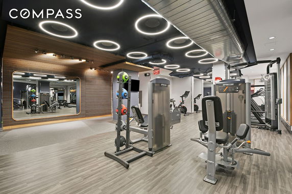Modern gym area with exercise equipment and circular lighting on the ceiling.