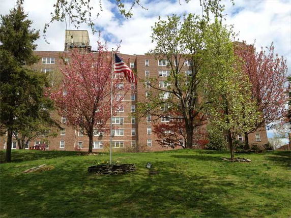 Front view of a multi-story apartment building with a flagpole in front.