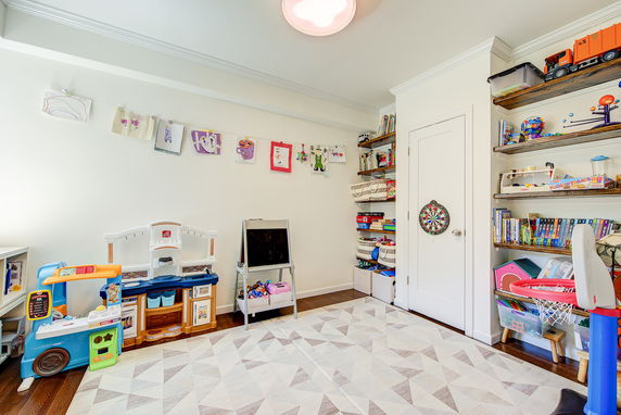 Indoor children's play area with toys, bookshelves, and colorful drawings on the wall.