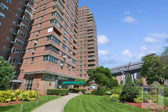 Front view of a multi-story apartment building with a garden area.