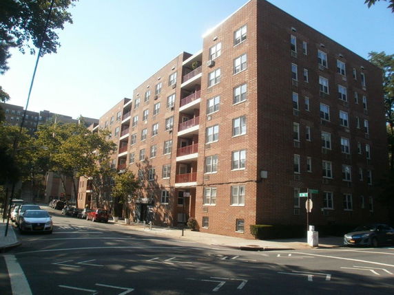 Front view of a multi-story brick apartment building on a street corner.