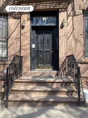 Front view of a building entrance with steps leading to a black door.