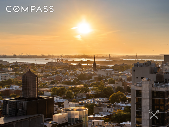 Panoramic view of a cityscape at sunset with industrial buildings and water tower.