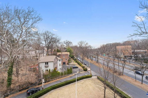 Elevated view of residential area with houses and roads surrounded by trees.