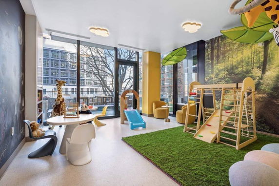Room with play equipment and toys, featuring a large window and colorful decor.