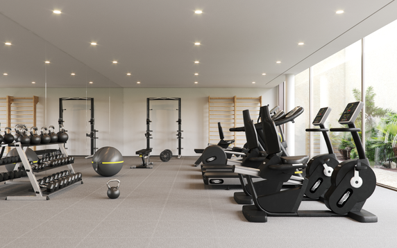 Interior view of a gym with exercise equipment including bikes, weights, and benches.