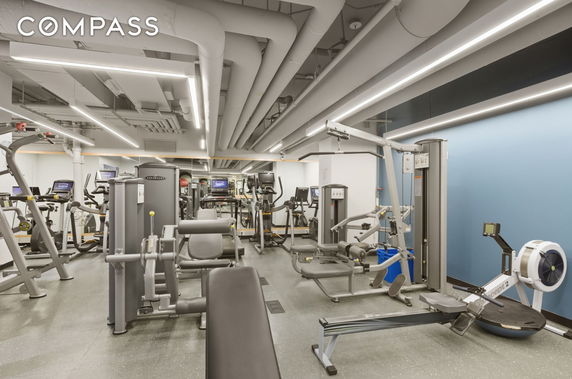 Interior view of a gym with various exercise equipment and mirrored walls.