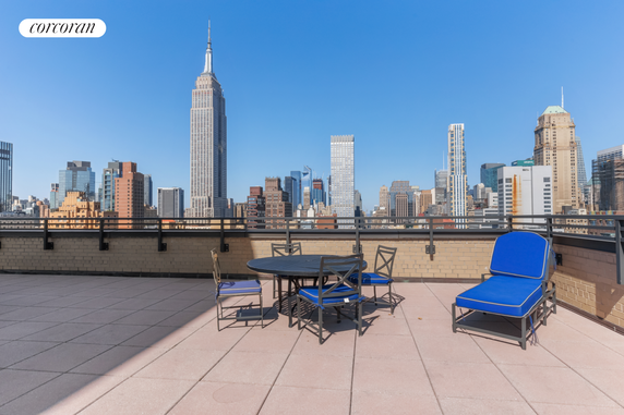 Rooftop terrace with outdoor seating and city skyline view.