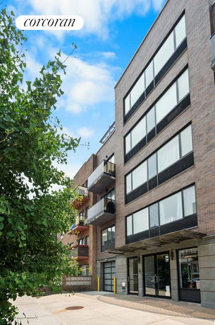 Front view of a modern multi-story building with balconies and large windows.
