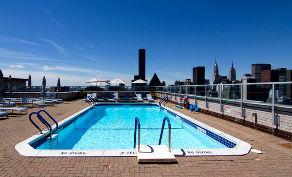 Rooftop swimming pool with city skyline in the background.