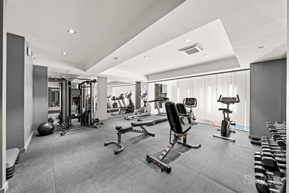 Indoor gym area with exercise equipment and weights.