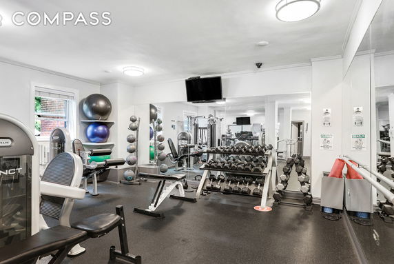 Indoor gym area with various exercise equipment and mirrors.