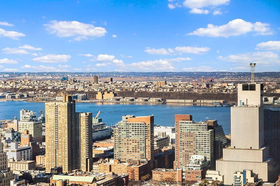 Panoramic view of a cityscape with a river and surrounding buildings.