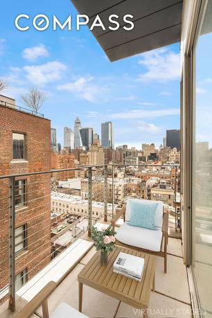 Panoramic view of a city skyline from a balcony with outdoor seating.