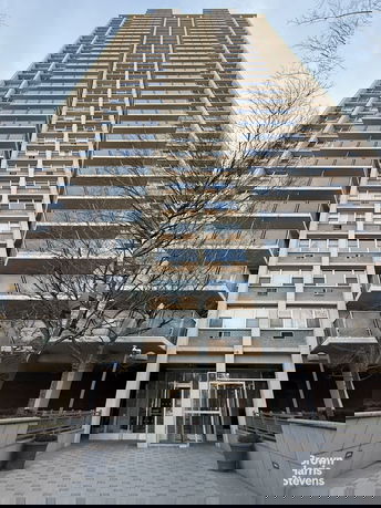 Front view of a tall residential apartment building with multiple balconies.