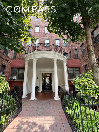 Front view of a multi-story brick building with a columned entrance.