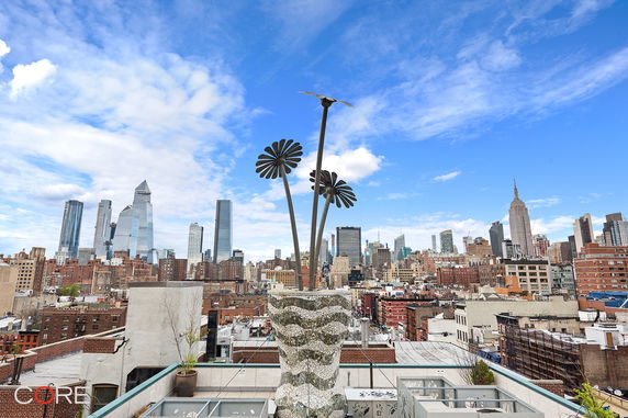 Rooftop view with a skyline and a decorative metal flower sculpture.