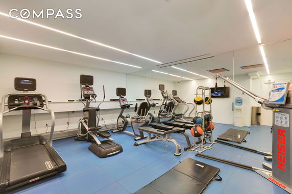 Indoor gym with exercise equipment including treadmills, elliptical machines, and weights.