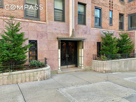 Front view of a building entrance with decorative iron doors and stone facade.