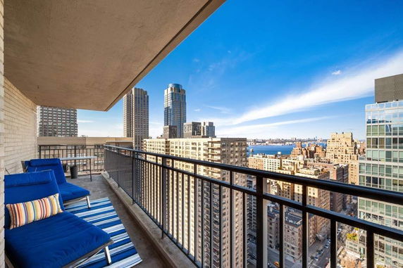 Balcony view over city skyline with river and tall buildings.