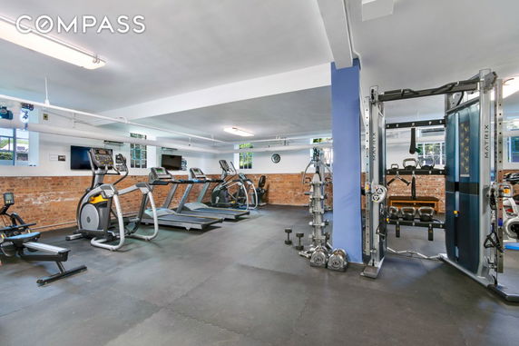 Interior view of a gym with exercise equipment including treadmills and weight machines.