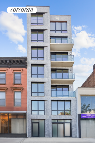 Front view of a multi-story modern building with large windows and balconies.