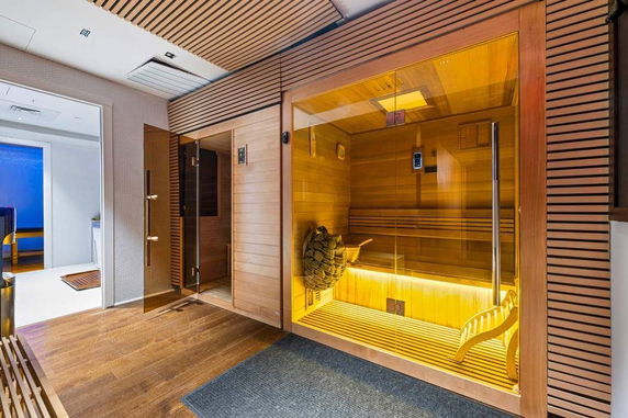 Interior view of a sauna room with wooden panels and glass door.