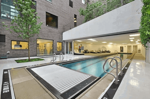View of a building with an outdoor swimming pool and adjacent lounge area.