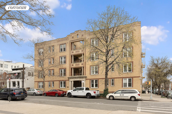 Front view of a multi-story brick apartment building with symmetrical windows and a central entrance.