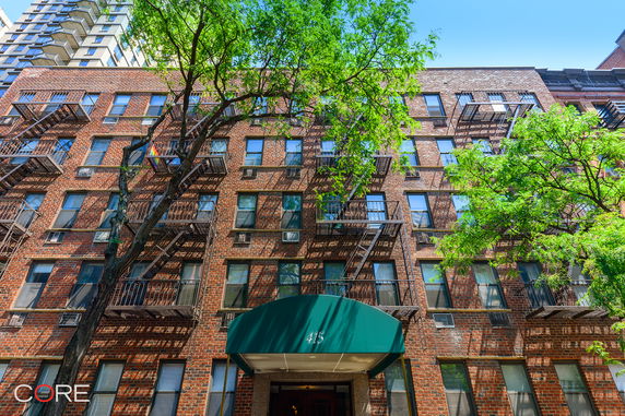 Front view of a multi-story brick apartment building with fire escapes.