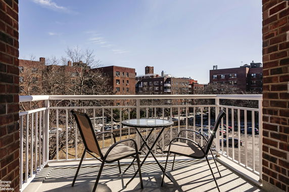 Balcony view overlooking apartment buildings and a parking area.