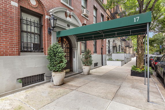 Front view of a brick apartment building entrance with a green awning.