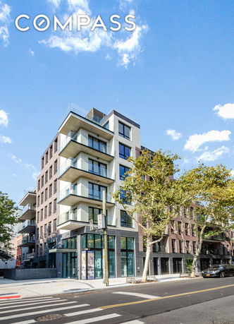 Front view of a modern multi-story apartment building with balconies.