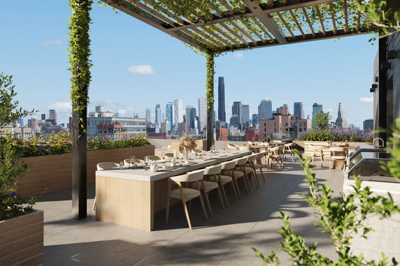 Rooftop area with tables and chairs under a pergola, overlooking city skyline.