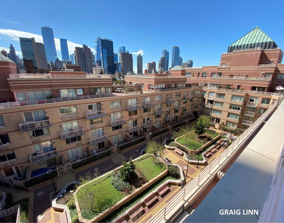 View of residential buildings with a courtyard, set against a city skyline.