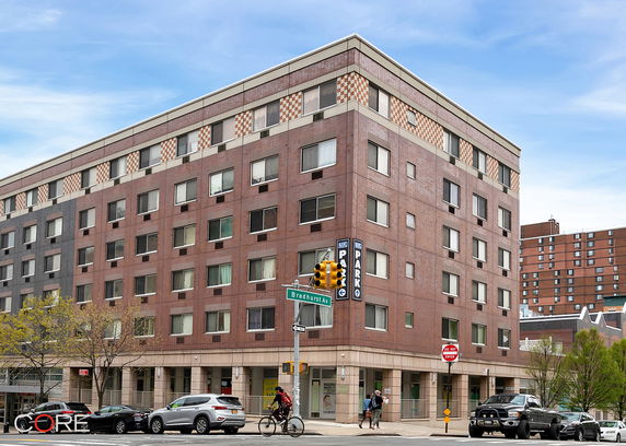 Front view of a multi-story building at a street corner with parking signage.