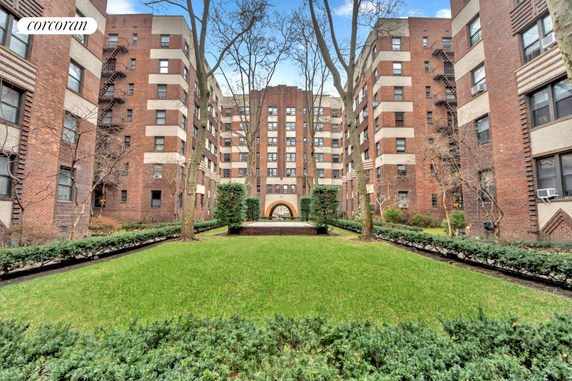 Front view of a multi-story brick residential building with a central archway entrance.