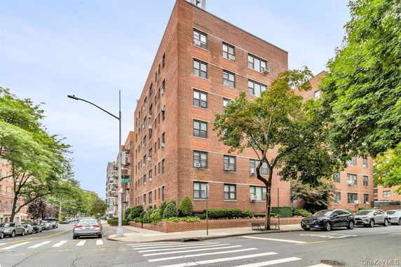 Front view of a multi-story brick apartment building on a street corner.