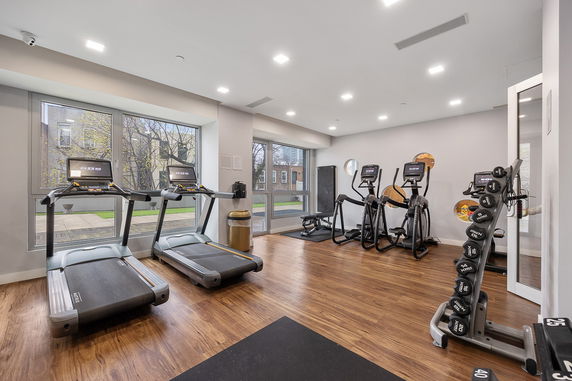 Indoor gym with exercise equipment and large windows.