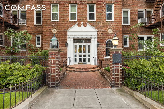 Front view of a multi-story brick building with a central entrance and white trim.
